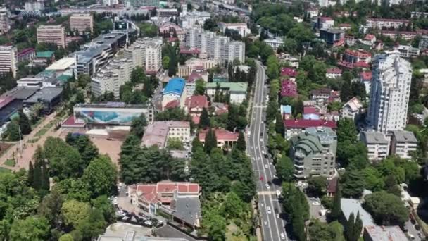 Videooptagelse fra luften. Panorama fugle-øje udsigt over byens centrum af Sochi. En klar solskinsdag. Byen på baggrund af høje bjerge. Tæt bygning. – Stock-video