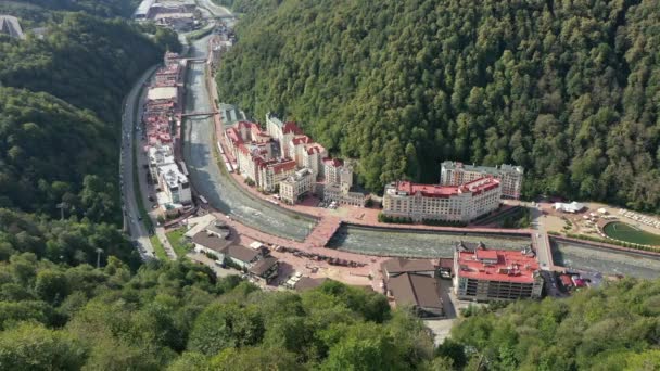 Rosa Khutor balneario alpino de Sochi, ayuntamiento, puente peatonal, Rathaus y vista a la plaza central en el día soleado. Roza Khutor. Montañas. Día soleado. Hoteles. Río Mzymta. Krasnaya polyana. — Vídeos de Stock