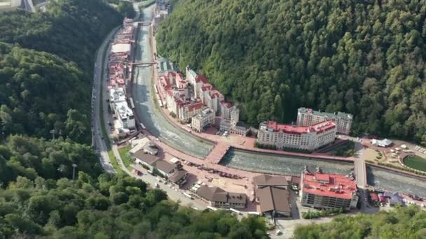 Rosa Khutor balneario alpino de Sochi, ayuntamiento, puente peatonal, Rathaus y vista a la plaza central en el día soleado. Roza Khutor. Montañas. Día soleado. Hoteles. Río Mzymta. Krasnaya polyana. — Vídeos de Stock