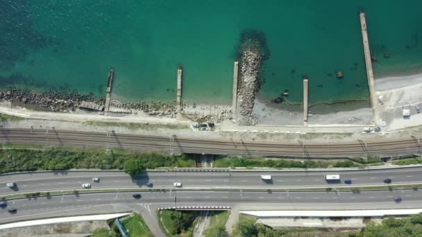 从空中俯瞰沿著海岸线的高速公路.无人机飞越海岸和陆地上的道路. — 图库视频影像