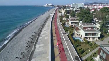 Hava videosu. Sochi 'nin olimpiyat seti. Kumsal. Karadeniz. Tatil sezonu. Modern şehir manzarası, Rusya 'nın popüler sahil beldesi. Şehir otelleri konut binaları olimpiyat parkı manzarası. 