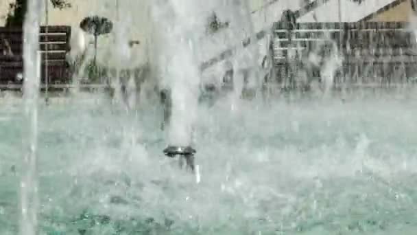在喷泉中的水滴和水花的近景。喷泉中的蓝色水闪烁着光芒. — 图库视频影像