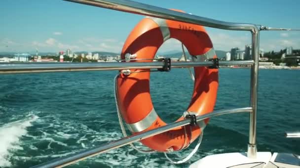 Red life buoy over blue calm sea water background. Lifebuoy on the boat. slow motion — Stock Video