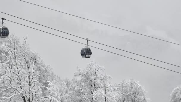 Winterpanorama mit Skiliften und schneebedeckten Bergen. Zweierseilbahn auf einer Skipiste im winterlich verschneiten Wald. — Stockvideo