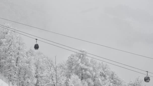 Zimní panorama s lyžařskými vleky a zasněženými horami. dvousedačková lanovka na sjezdovce v zimním zasněženém lese. — Stock video