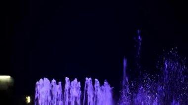 Su sıçratıyorum. Renkli çeşme ve renkli gece ışıkları. Aydınlatılmış su çeşmesi. Drops, kapat. Çeşmeden su fışkırıyor. 