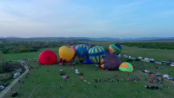 Luchtfoto van een ochtendlancering van heteluchtballonnen op een ballonfestival van Filling up to Take Off. — Stockvideo