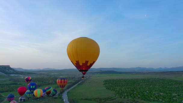 Balão de ar quente amarelo no céu azul. O balão voa sobre as árvores. Bela cena romântica de verão. vista aérea — Vídeo de Stock