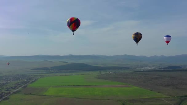 Viele Heißluftballons fliegen über Täler. Heißluftballons starten im Morgengrauen — Stockvideo