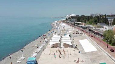 Hava videosu. Sochi 'nin olimpiyat seti. Kumsal. Karadeniz. Tatil sezonu. Modern şehir manzarası, Rusya 'nın popüler sahil beldesi. Şehir otelleri konut binaları olimpiyat parkı manzarası. 