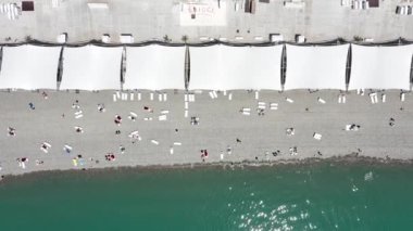 Kalabalık bir sahil tatili manzarası. Plaj yazında eğleniyorum. Hava görüntüsü. Güneş şemsiyelerinin yukarıdan görünüşü ve plajda dinlenen insanlar. eğlenceli tropikal tatil ve yaz geçmişi