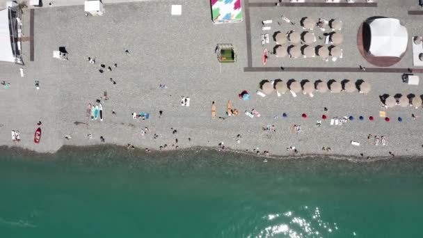 사람많은 해변 방학 최고 전망. 해변에서 재밌게 놀고 있어. 공중에서 본 모습. 햇빛 우산 과 해변에서 쉬고 있는 사람들 이 공중에서 내려다본 맨 위에 보이는 광경. 즐거운 열 대의 휴가와 여름 배경 — 비디오