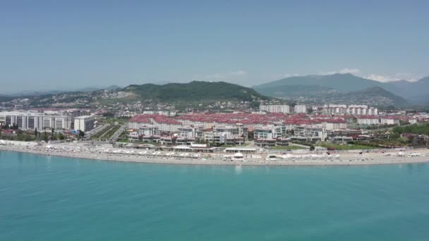 Urlaubsorte und Strand aus der Luft. Blick auf einen wunderschönen Strand eines Ferienortes in Sotschi mit kristallklarem Meer und Menschen im Urlaub. — Stockvideo