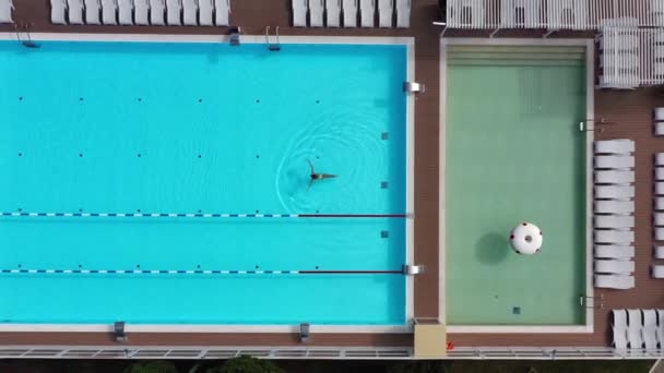 室外游泳池，有荡漾的蓝色碧绿的水和钢制栏杆楼梯。梯度不锈钢扶手下降到游泳池。公众游泳池的空中景观 — 图库视频影像