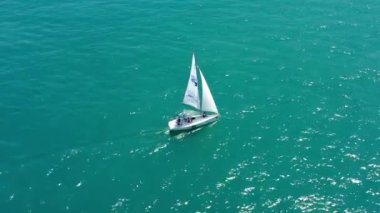 Açık denizde yat gezintisi. Yelkenli. İHA 'dan gelen yat. Hava videosu. İHA 'dan yelkenliye. Rüzgarlı bir günde yat. Açık deniz. Mavi bulutlu arka planda yarışma sırasında küçük yelkenli tekneler.
