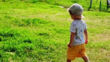 Yeşil toplu komik küçük bir çocuk. Sabit çekim. Ağır çekim. Küçük bir oğlan. Sevimli bebek gülümsüyor. Yakışıklı bir çocuk. Çocuk kameraya gülüyor. Doğadaki çocuk piknik yapıyor.. 