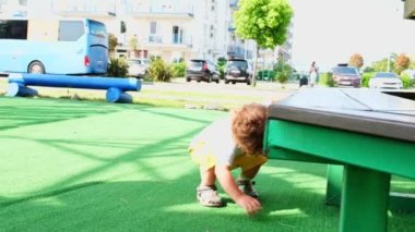 Yeşil toplu komik küçük bir çocuk. Sabit çekim. Ağır çekim. Küçük bir oğlan. Sevimli bebek gülümsüyor. Yakışıklı bir çocuk. Çocuk kameraya gülüyor. Doğadaki çocuk piknik yapıyor.. 