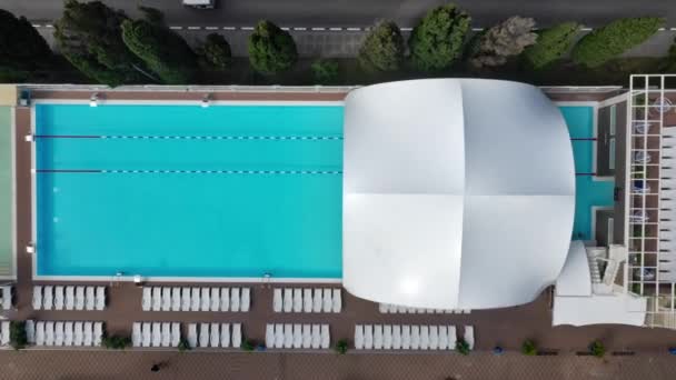 Piscina exterior con agua azul turquesa ondulada y escaleras de acero. Escalera pasamanos de acero inoxidable para el descenso a la piscina. Vista aérea de la piscina pública — Vídeo de stock