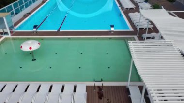 Açık havuz, dalgalı mavi turkuaz su ve çelik parmaklıklı merdivenler. Yüzme havuzuna inmek için merdiven paslanmaz tırabzanlar. Halka açık yüzme havuzunun hava manzarası