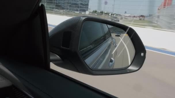 Coche negro en movimiento, la carretera se refleja en el espejo de visión lateral, espejo de larga distancia del automóvil. Otro coche está siguiendo en la parte posterior del coche en movimiento. desde el retrovisor lateral. — Vídeos de Stock