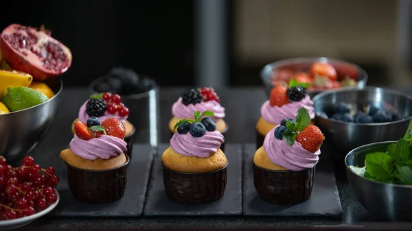 Professional pastry. Decorating cup cakes with mint, strawberry and blueberry Stock Image