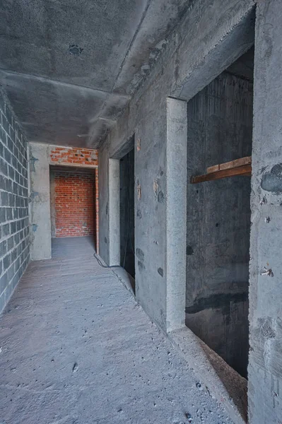 Empty concrete elevator shaft in building. Walls are not plastered. Repair works on construction site of residential apartments. Hallway in new building without repair.