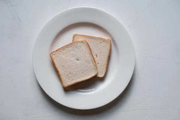 Beyaz tabakta izole edilmiş dilimlenmiş tost ekmeği. — Stok fotoğraf