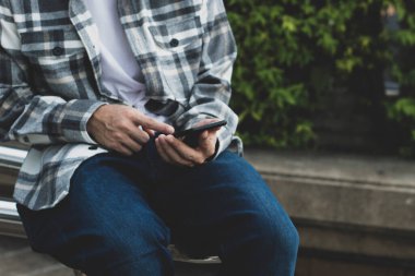 online ağ teknolojisi için akıllı telefon kullanan genç çocuk; kamu parkında cep telefonu kullanan adam