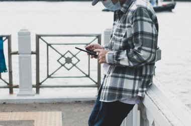 online ağ teknolojisi için akıllı telefon kullanan genç çocuk; kamu parkında cep telefonu kullanan adam