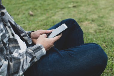 online ağ teknolojisi için akıllı telefon kullanan genç çocuk; kamu parkında cep telefonu kullanan adam