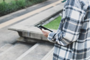 online ağ teknolojisi için akıllı telefon kullanan genç çocuk; kamu parkında cep telefonu kullanan adam