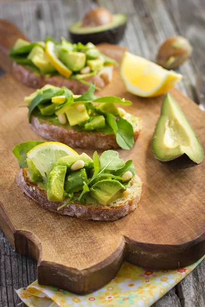 Bruschetta met avocado, rucola, citroen en pijnboompitten — Stockfoto