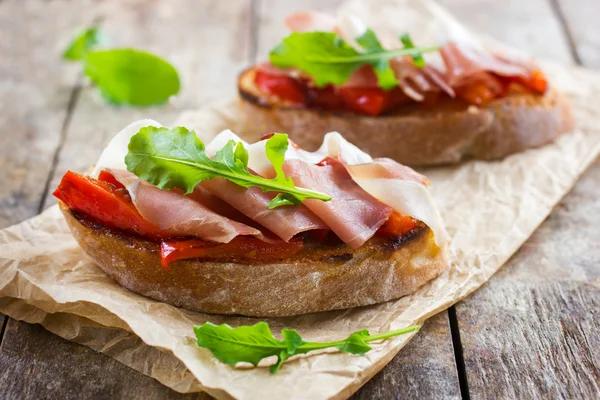 Bruschetta dengan paprika panggang, prosciutto dan arugula — Stok Foto