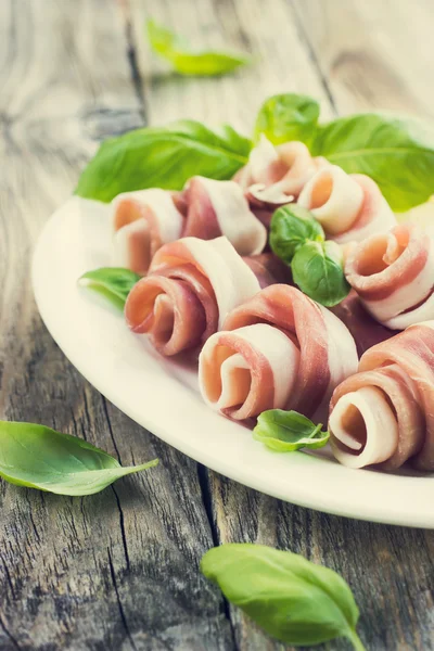 Prosciutto with basil on a white plate — Stock Photo, Image