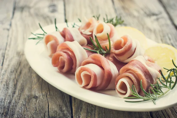 Prosciutto with rosemary on a white plate — Stock Photo, Image