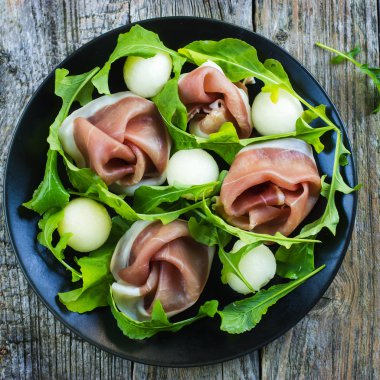 Salad with prosciutto, melon and arugula clipart