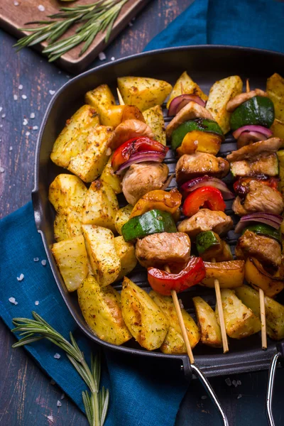 Мясо на гриле, овощные кебабы и запечённая картошка на сковороде — стоковое фото