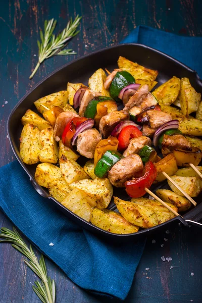 Grilled meat and vegetable kebabs and baked potatoes on pan — Stock Photo, Image