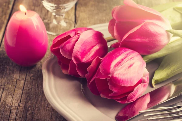 Frühlingstisch mit drei rosa Tulpen und Kerzenei zu Ostern — Stockfoto