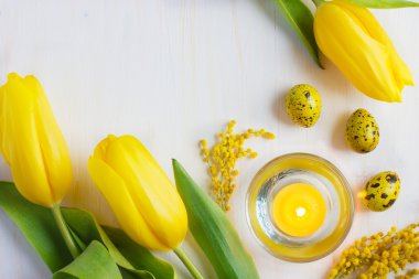 Easter background with candle, yellow eggs  and tulips, top view clipart