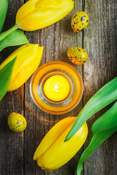 Oeufs de Pâques, bougie et tulipes sur fond bois, vue de dessus — Photo