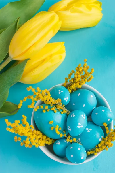 Velikonoční vajíčka a tulipány na modrém pozadí — Stock fotografie