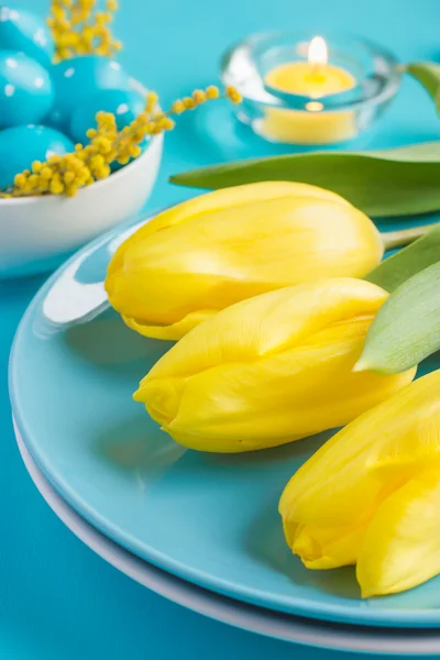 Ostertischdekoration mit gelben Tulpen und Eiern auf blauem Hintergrund — Stockfoto