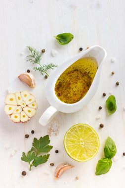 Ingrediets for salad dressing. Olive oil, garlic, lemon, herbs a clipart