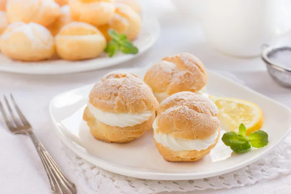 Profiteroles with cream and powdered sugar — Stock Photo, Image