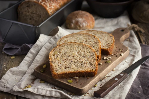 Frisches Mehrkornbrot auf rustikalem Hintergrund — Stockfoto