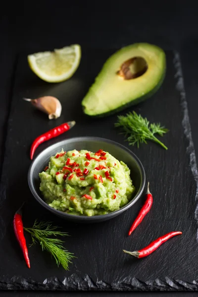 Guacamole dip and ingredients on black background — Stock Photo, Image