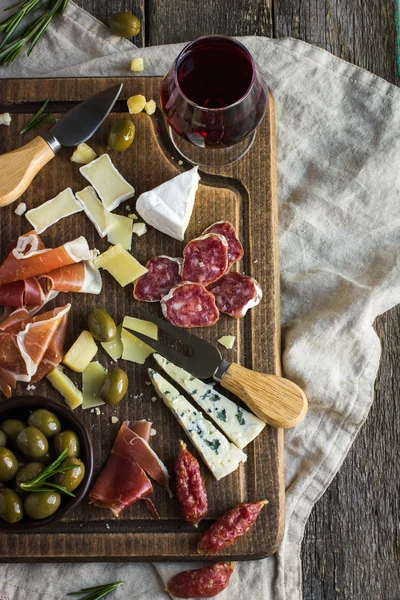 Assortment of various types of cheese and meat on wooden board — Stock Photo, Image
