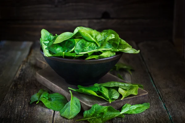 Fresh spinach in bowl on wooden background — Stock Photo, Image