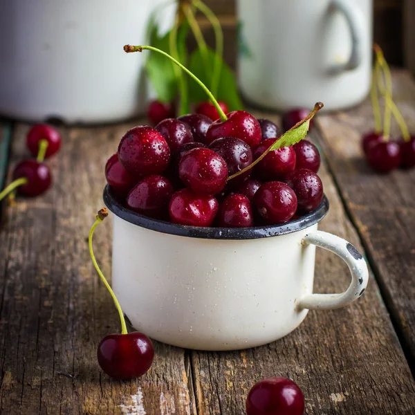 Fresh cherries in enamel mug — Stock Photo, Image
